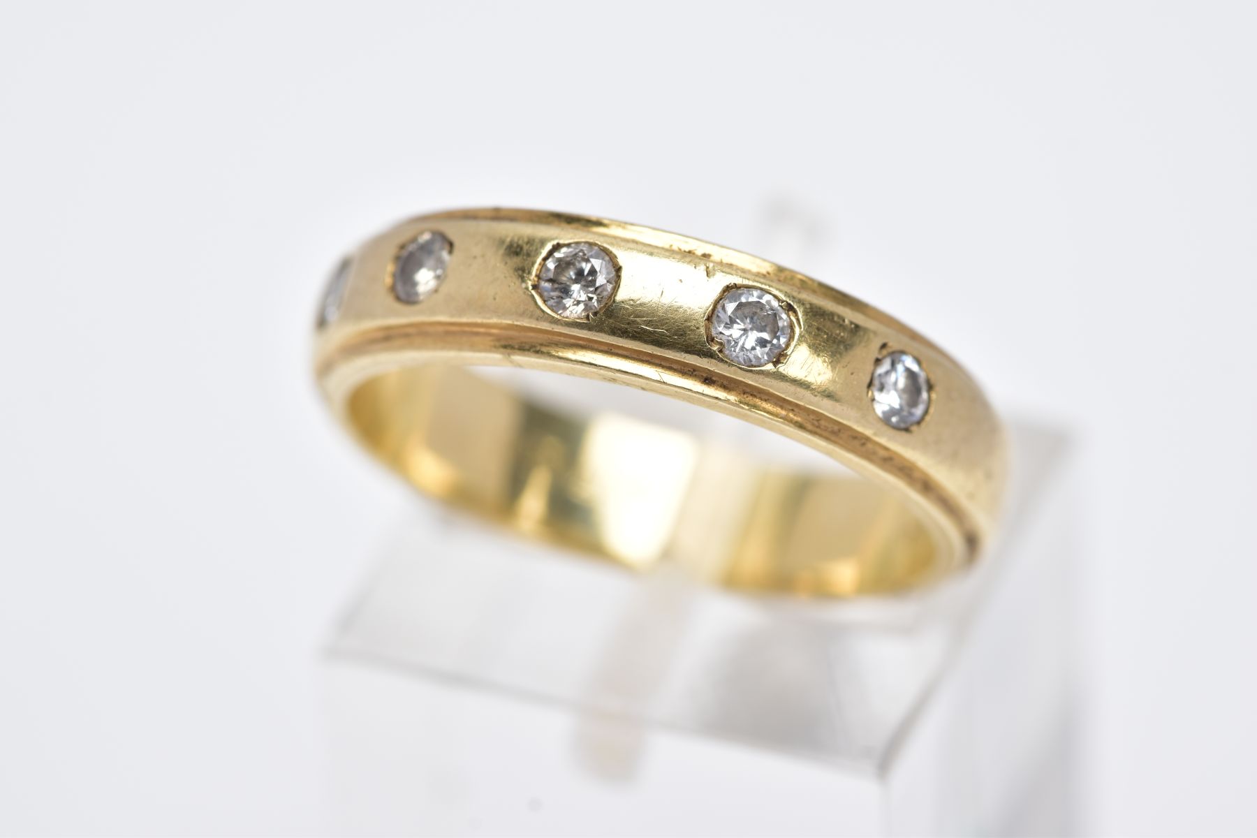 A 9CT GOLD DIAMOND BAND, a plain polished band set with five round brilliant cut diamonds, each