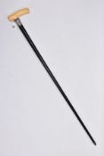 AN EBONISED WOOD WALKING CANE, fitted with a carved ivory handle, silver mounted rim with an