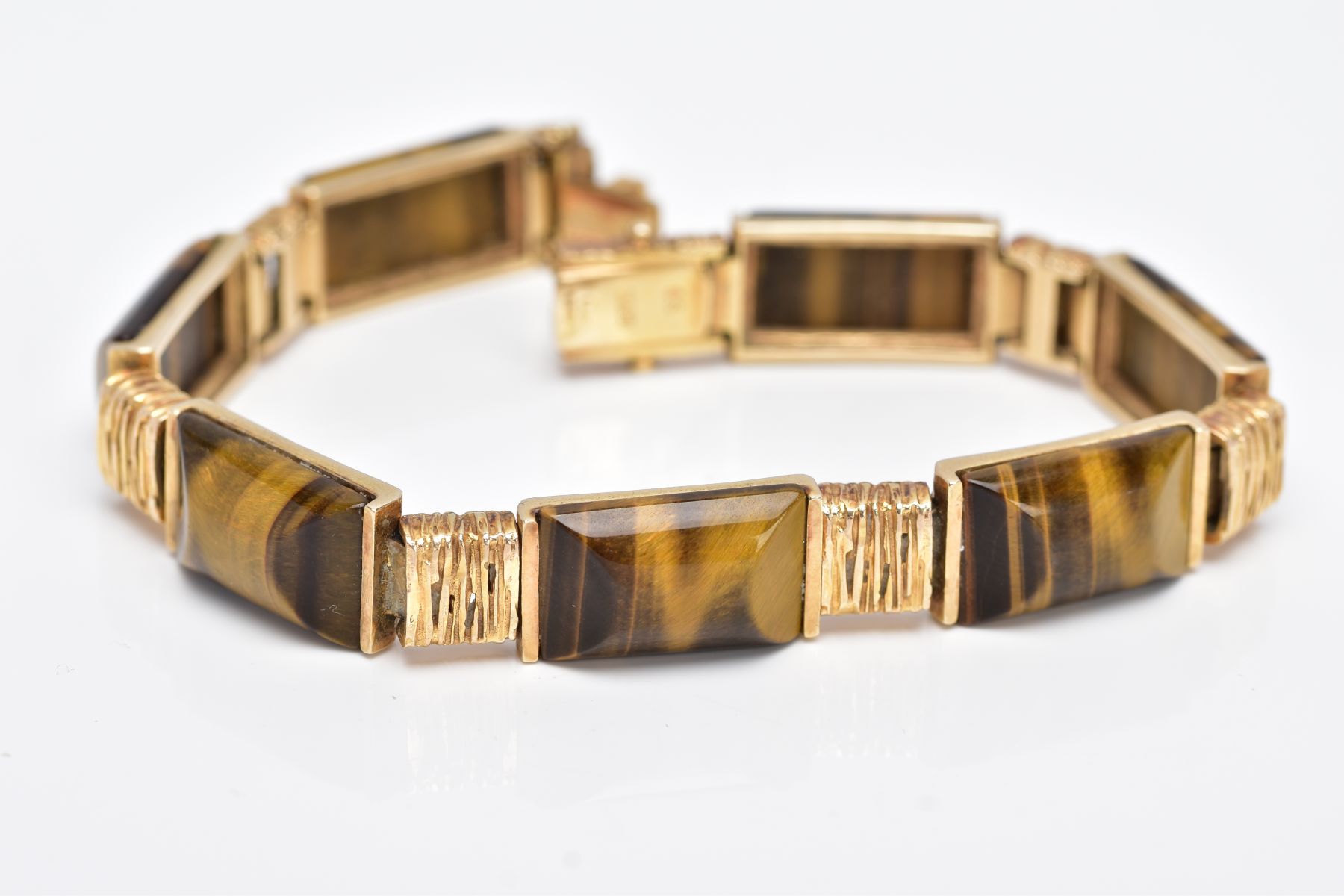 A 9CT GOLD TIGERS EYE LINE BRACELET, designed with seven rectangular shaped links set with