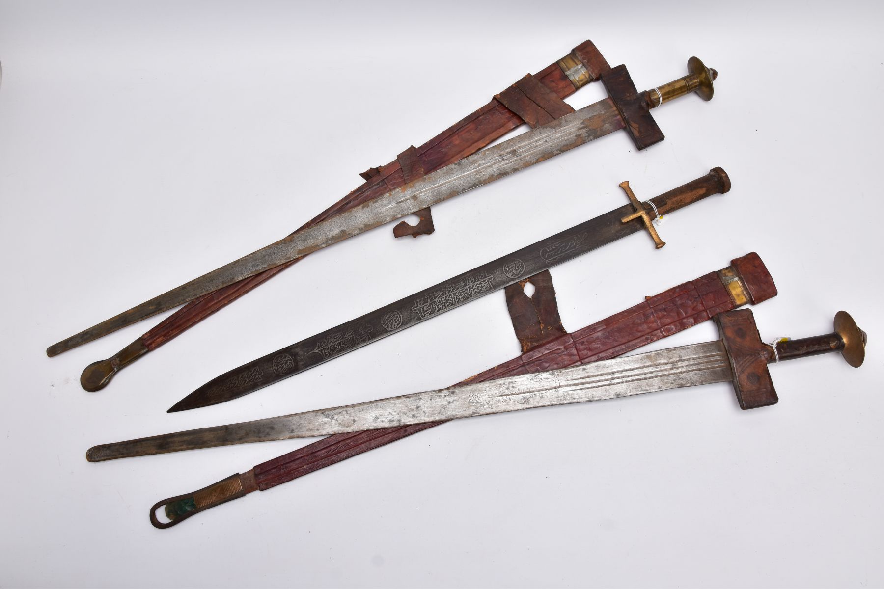 AN ARABIC DESIGN SHORT SWORD, wooden grip with gold coloured metal cross guard, blade has Arabic