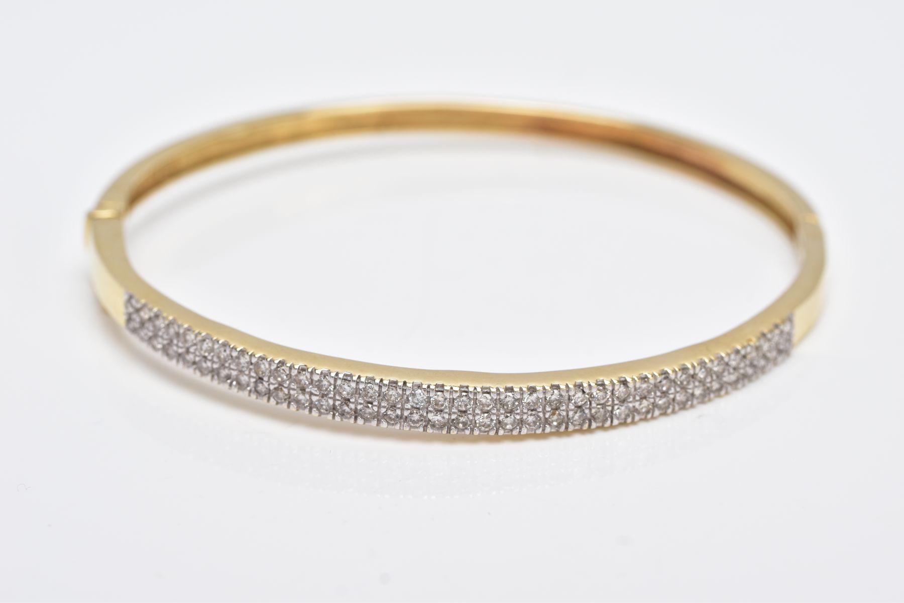 A YELLOW METAL DIAMOND BANGLE, the hinged bangle designed with two rows of round brilliant cut