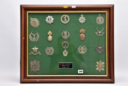 A LARGE GLAZED FRAME APPROXIMATELY 59CM X 49CM CONTAINING EIGHTEEN MILITARY RELATED CAP/HELMENT