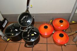 TWO SETS OF THREE GRADUATED LE CREUSET SAUCEPANS AND LIDS, one set in orange enamel with pouring
