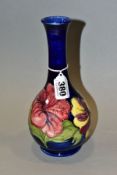A WALTER MOORCROFT POTTERY BOTTLE SHAPED VASE, the blue ground decorated with pink and yellow/purple