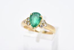 A YELLOW METAL EMERALD AND DIAMOND RING, designed with a central claw set, pear cut emerald, flanked