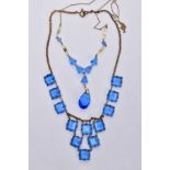 TWO BLUE PASTE SET NECKLACES, the first set with square blue paste on a brass toned curb link chain,