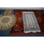 A PAIR OF MODERN RED GROUND RUGS, 200cm x 125cm, a circular rug, a tekke rug and a bed throw (5)