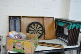 A VINTAGE MILITARY CAMP BED, another camp bed frame, a dartboard in cabinet and a box of cables
