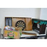 A VINTAGE MILITARY CAMP BED, another camp bed frame, a dartboard in cabinet and a box of cables