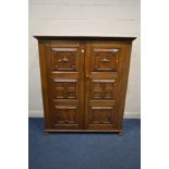 A REPRODUCTION OAK DOUBLE DOOR WARDROBE, of low proportions and geometric panelling, on flat bun