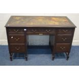 AN EDWARDIAN MAHOGANY DESK, with a distressed leather top, and seven drawers, width 123cm x depth