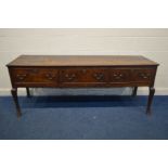 A GEORGIAN OAK PLANK TOP DRESSER BASE, with three drawers, brass drop handles on square cabriole