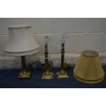 A PAIR OF BRASS CORNITHIAN TABLE LAMPS with gold fabric shades, and another brass table lamp with