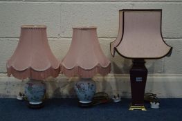 A BURGUNDY CERAMIC TABLE LAMP and a pair of floral ceramic table lamps, all with pink fabric