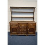 A GEORGIAN OAK AND MAHOGANY BREAKFRONT DRESSER, later plate rack top, the base with three drawers,