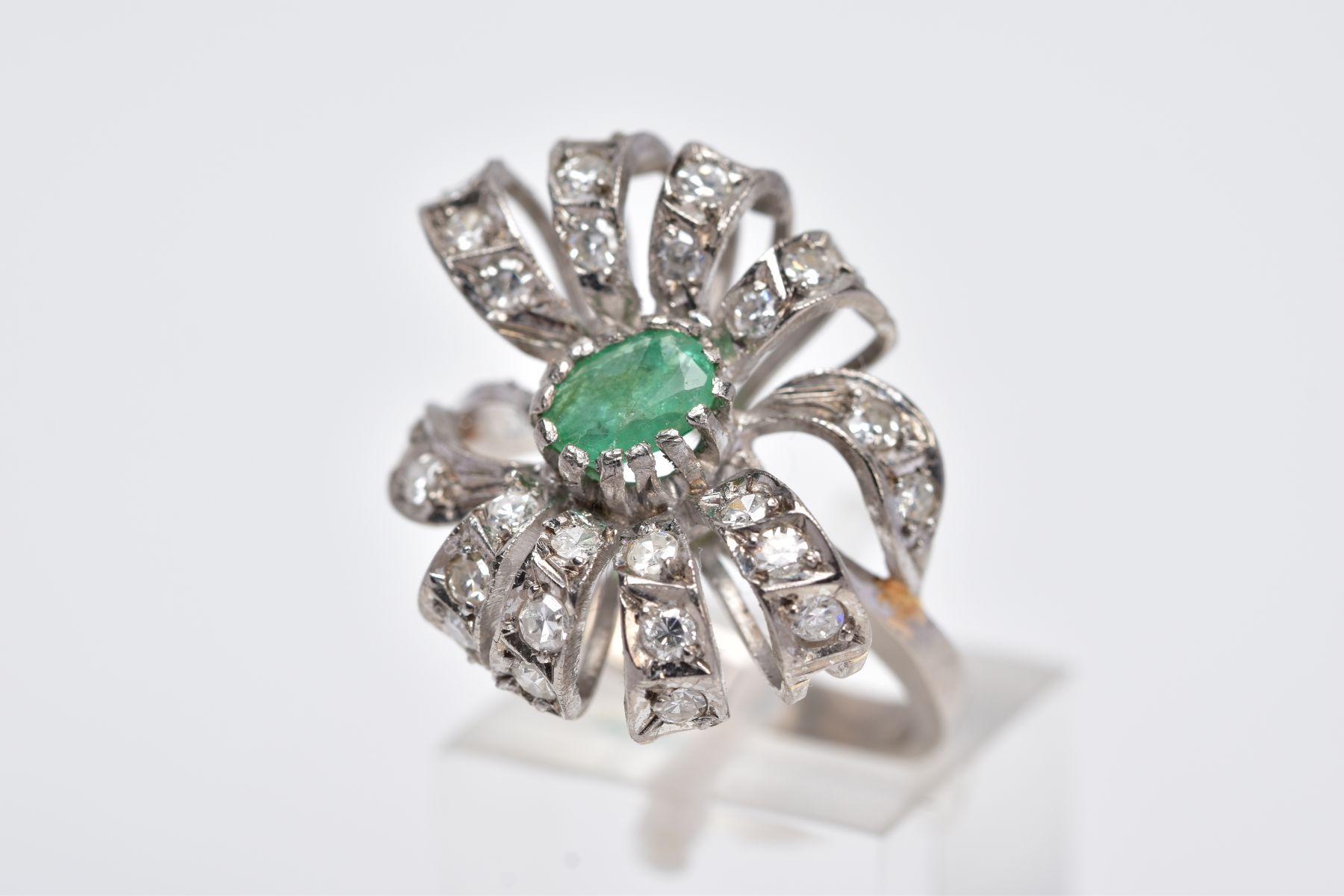 A WHITE METAL EMERALD AND DIAMOND RING, set with a central oval cut emerald (internal fracture