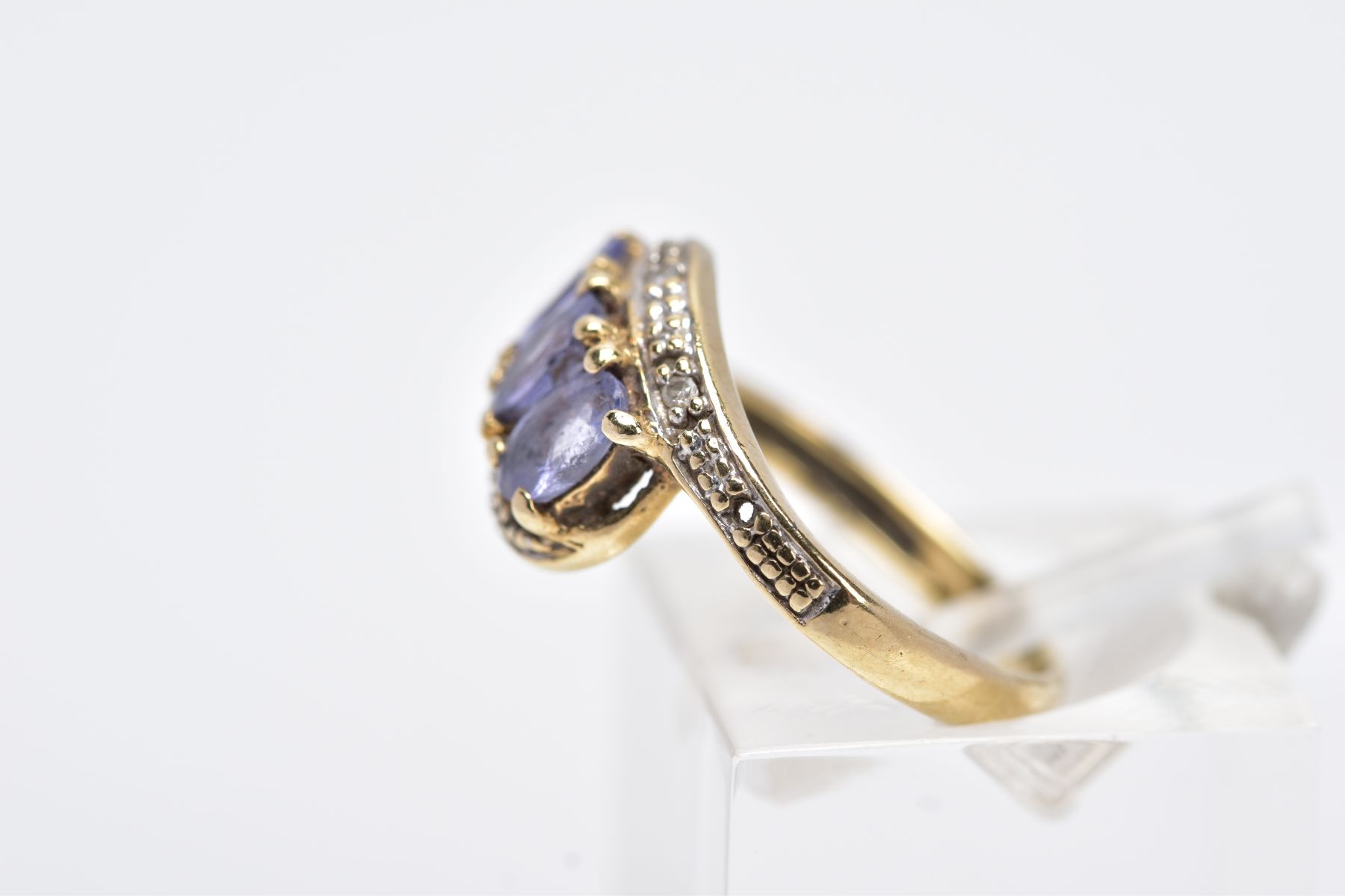 A YELLOW METAL GEM SET RING, of a crossover design, set with three oval cut purple stones assessed - Image 2 of 3