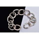 A SILVER BRACELET, designed with twelve hammer effect, wide circular links, slide through designed