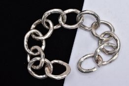 A SILVER BRACELET, designed with twelve hammer effect, wide circular links, slide through designed