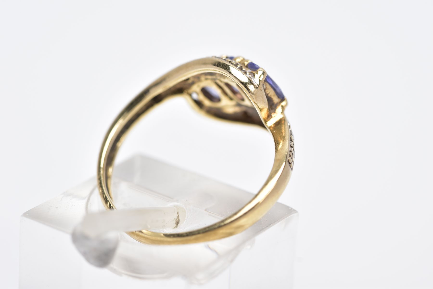 A YELLOW METAL GEM SET RING, of a crossover design, set with three oval cut purple stones assessed - Image 3 of 3