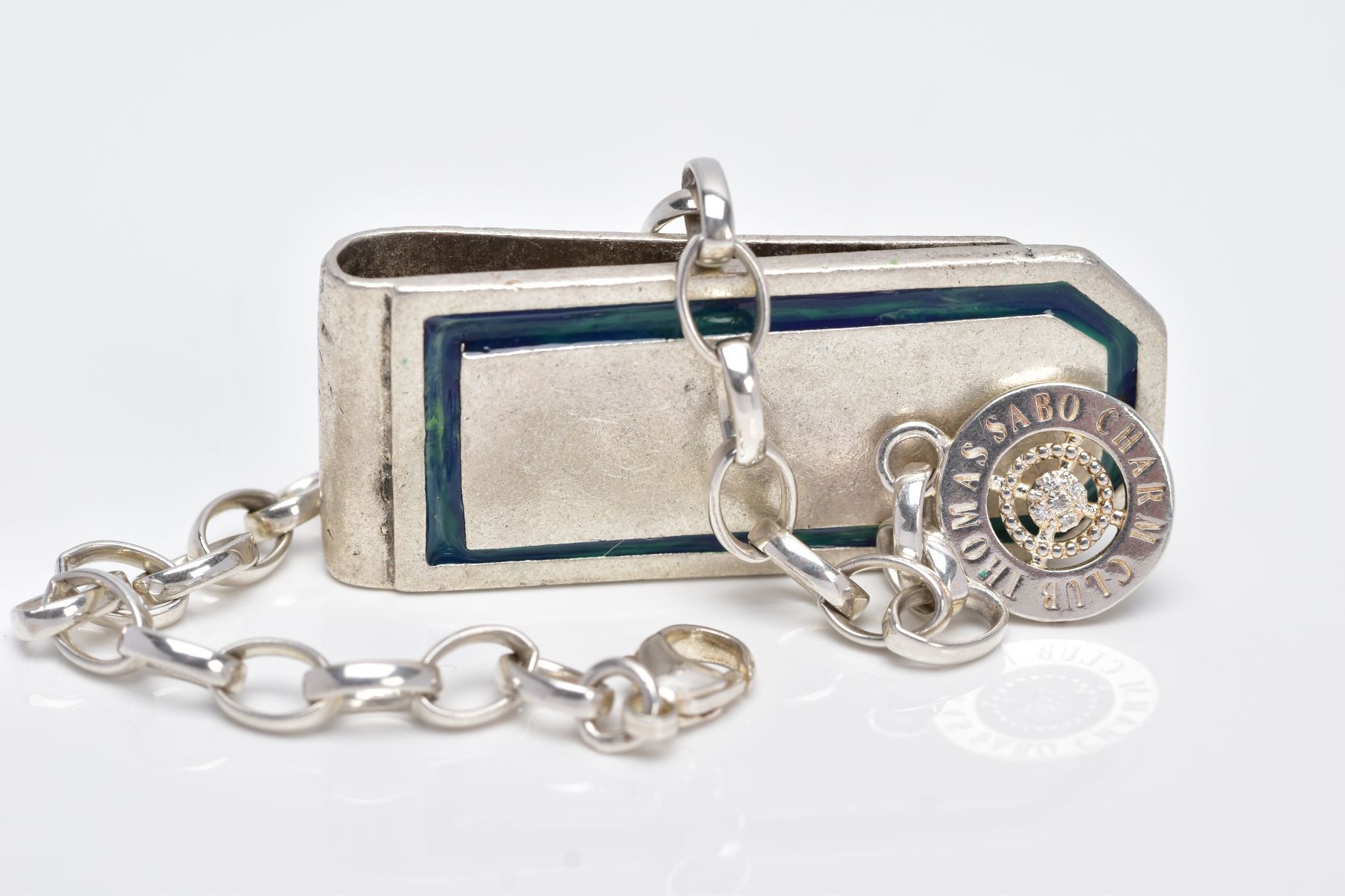 A WHITE METAL CHARM BRACELET AND A MONEY CLIP, the curb link bracelet fitted with a lobster claw