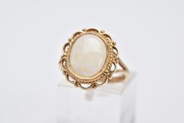 A 9CT GOLD OPAL RING, designed with an oval opal cabochon, within a collet mount and a scallop and