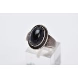 A GEORG JENSON ONYX RING, designed with a central oval onyx cabochon within a collet mount, plain