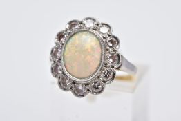 A WHITE METAL OPAL AND DIAMOND CLUSTER RING, designed with an oval opal cabochon, within a