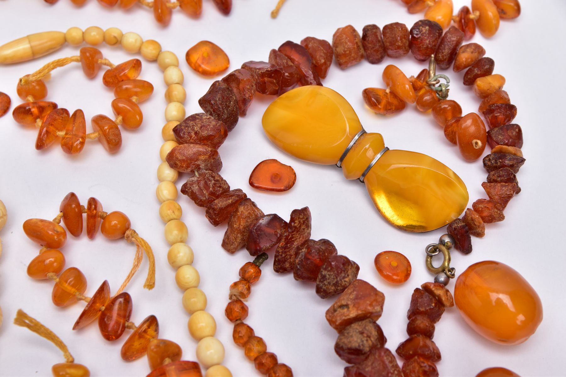 A TRAY OF AMBER AND CARVED IVORY BEAD NECKLACES AND A BROOCH, to include rough amber bead necklace - Image 4 of 6