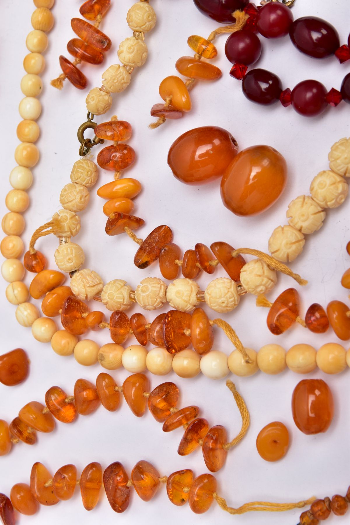 A TRAY OF AMBER AND CARVED IVORY BEAD NECKLACES AND A BROOCH, to include rough amber bead necklace - Image 5 of 6