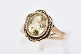 A 9CT GOLD CITRINE RING, designed with a central oval cut citrine within a collet mount, rope