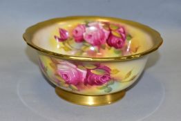 A ROYAL WORCESTER PORCELAIN FOOTED BOWL, decorated with sprays of roses and signed M. Hunt, puce