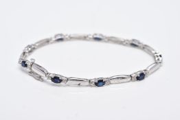 A 9CT WHITE GOLD, SAPPHIRE AND DIAMOND LINE BRACELET, designed with nine oval cut blue sapphires,