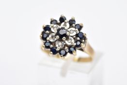 A 9CT GOLD SAPPHIRE AND DIAMOND CLUSTER RING, the raised cluster set with a claw set, circular cut
