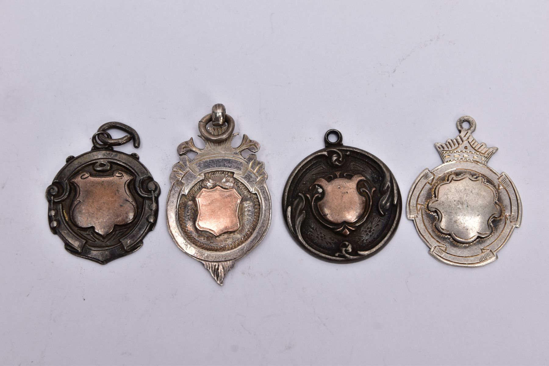 FOUR SILVER MEDAL FOBS, each of a circular form with vacant cartouches, two engraved to the