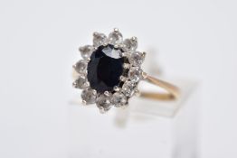 A 9CT GOLD CLUSTER RING, designed with a central oval cut blue sapphire, within a surround of claw