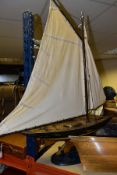A WOODEN POND YACHT, missing rudder, sails and rigging in need of some minor attention, playworn