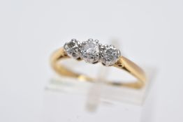 A YELLOW METAL THREE STONE RING, designed with two round brilliant cut diamonds and a single cut