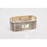 A SHAPED RECTANGULAR SILVER NAPKIN RING, engine turned decoration, initial C engraved to