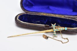 A YELLOW METAL SWORD STICK PIN, in the form of a sword set with a turquoise cabochon and white