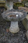 A COMPOSITE CLAM SHELL BIRD BATH on a brick effect support, height 47cm