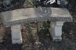 A WEATHERED COMPOSITE CURVED GARDEN BENCH on a pair separate bases, width 114cm x height 45cm