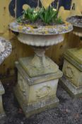 A LARGE WEATHERED RECONSTITUTED STONE CAMPANA GARDEN URN, on a separate square plinth base, diameter