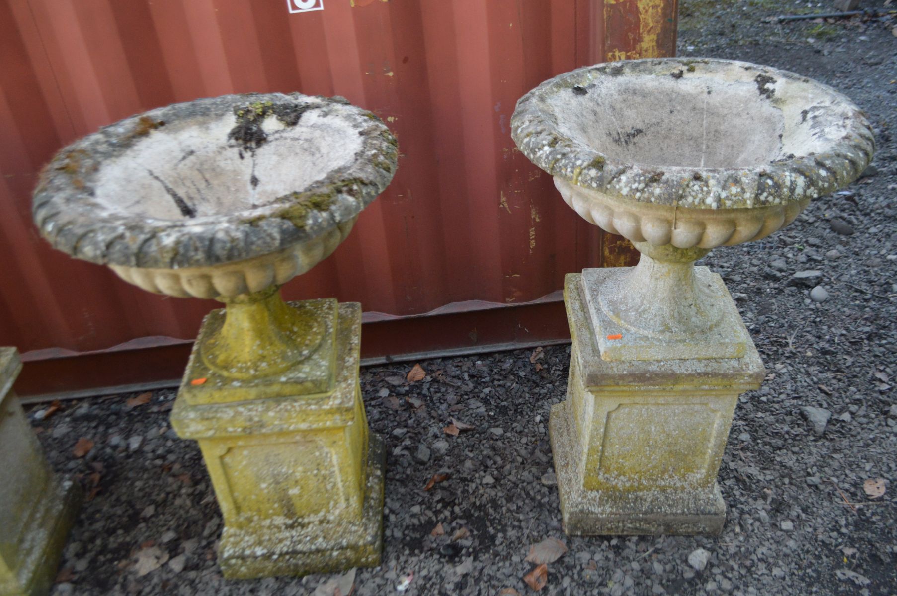 A PAIR OF WEATHERED RECONSTITUTED STONE CAMPANA GARDEN URNS on a separate square plinth base,