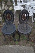 A PAIR OF HEAVY CAST IRON GARDEN CHAIRS, painted in the colour black, with ornate decoration and