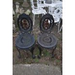 A PAIR OF HEAVY CAST IRON GARDEN CHAIRS, painted in the colour black, with ornate decoration and