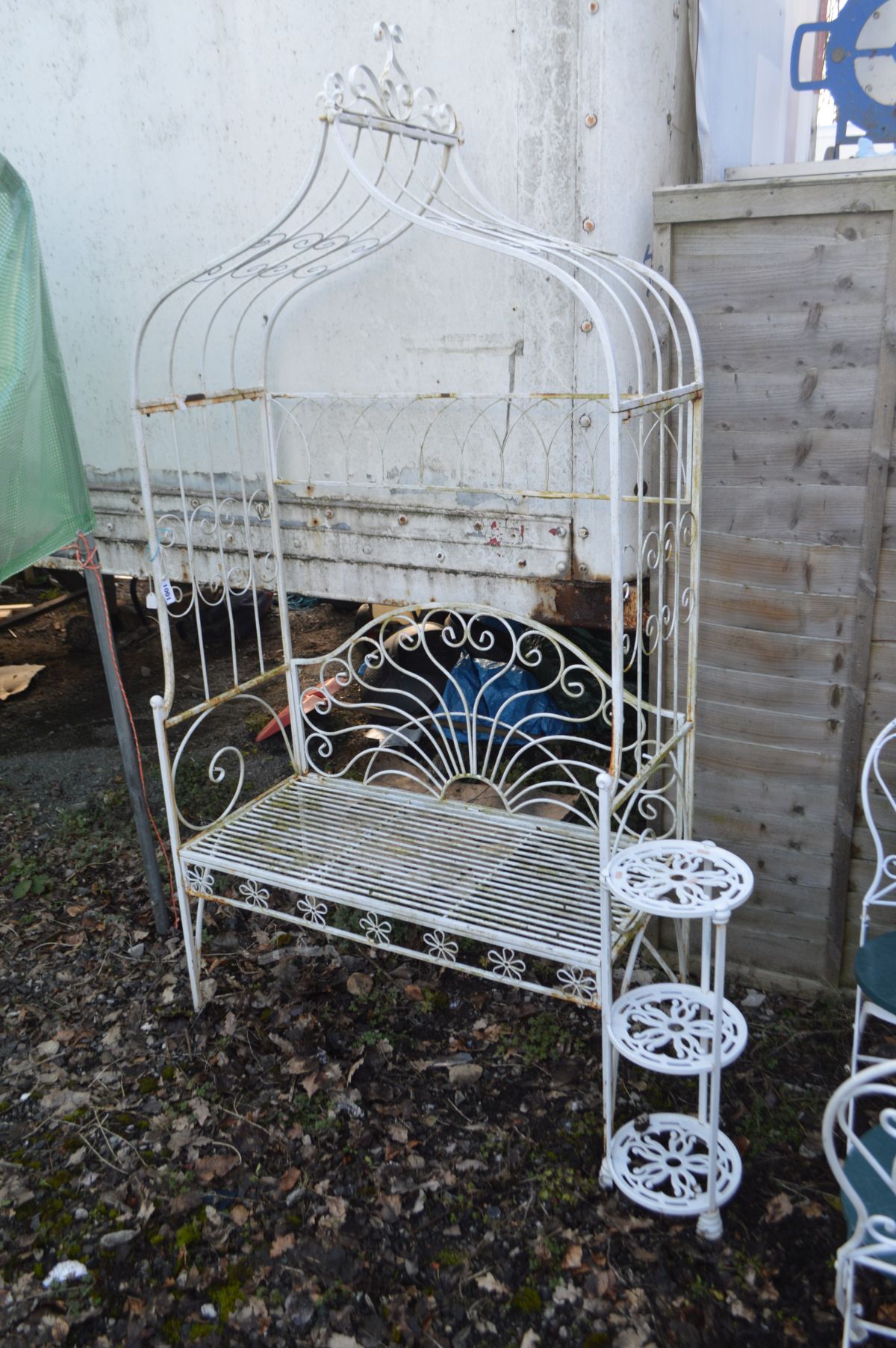 A WHITE PAINTED WROUGHT IRON GARDEN BENCH with an arched overhanging top, width 110cm x depth 51cm x