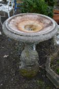 A LARGE COMPOSITE BIRD BATH, the circular top on a shaped twisted support, top diameter 69cm x