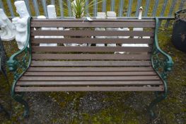 A HEAVY GREEN PAINTED METAL AND TEAK SLATTED BENCH, with lions head to the armrests, width 131cm