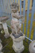 A COMPOSITE GARDEN STATUE OF A SEATED CHERUB/PUTTO, holding a bunch of grapes, on a separate